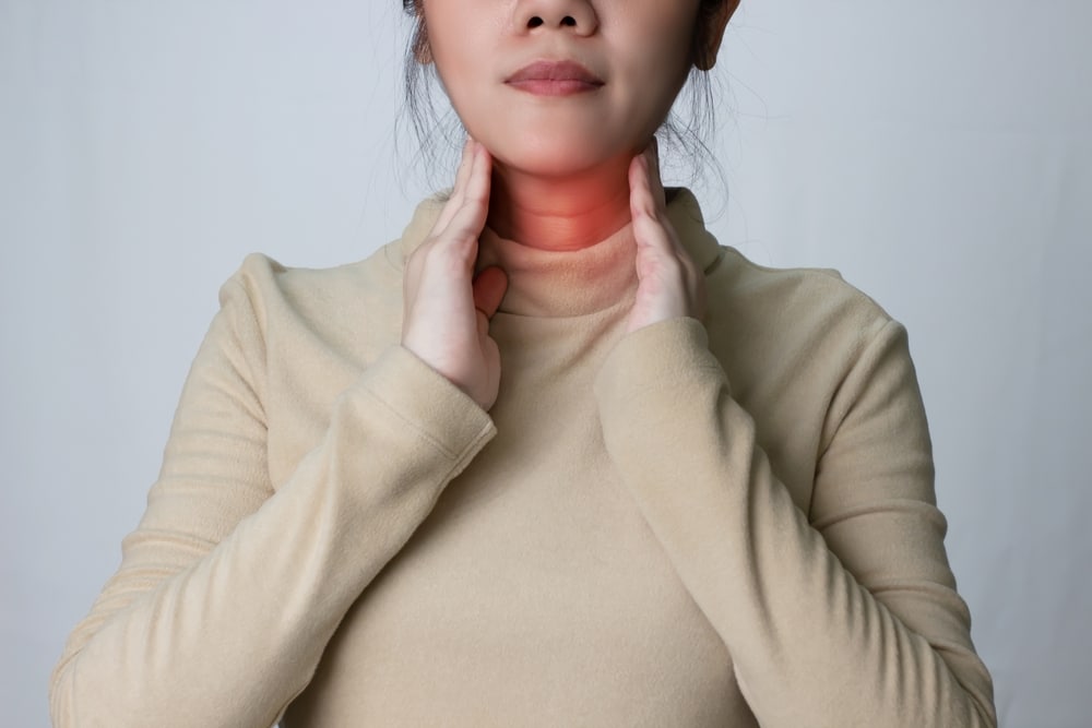 Woman holding her neck in pain, unsure if it’s a sore throat or if it’s a more serious case of strep throat.