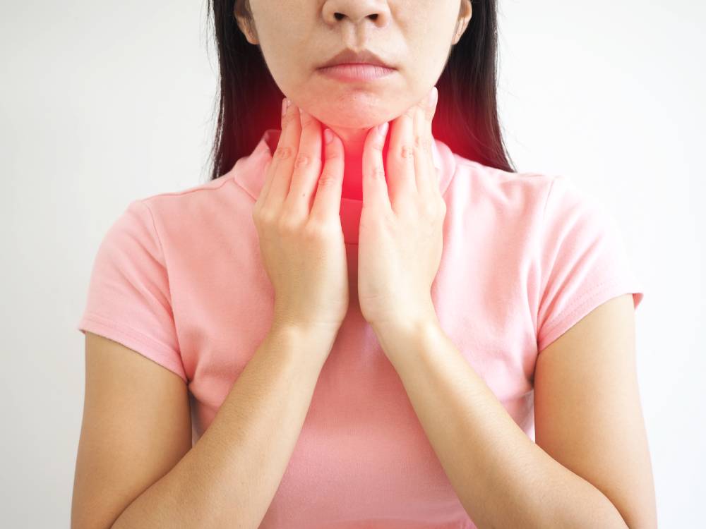 Asian woman sores her sore throat due to a bacterial infection. She needs antibiotics to cure her strep throat.