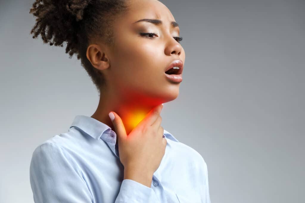 A woman with strep throat with her hand on her neck