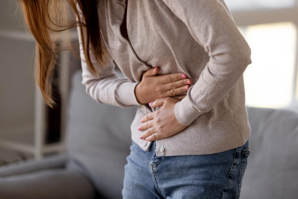 A woman with constipation bent over and holding her stomach