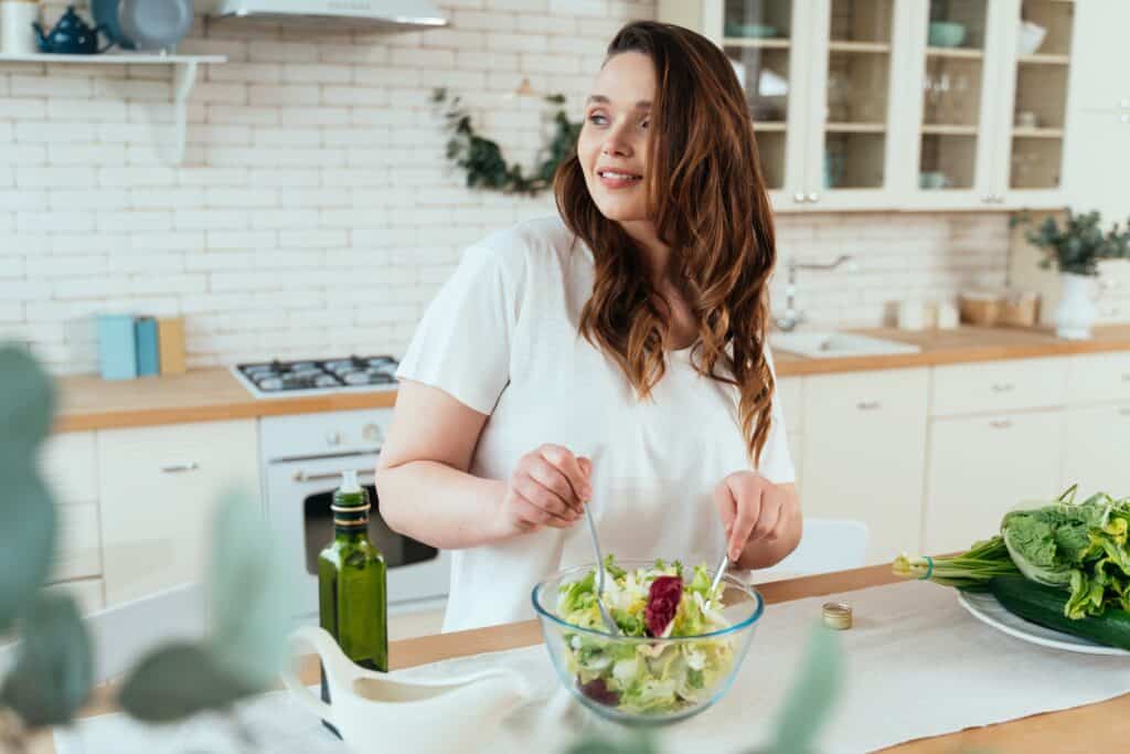 A woman making a salad in her kitchen