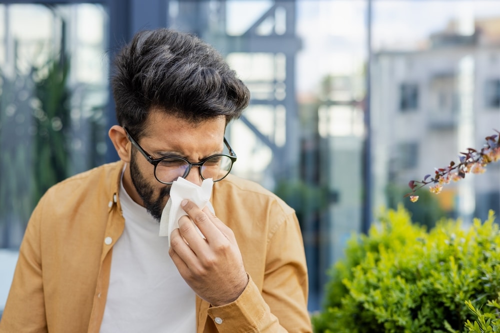 A man with allergies sneezing into a tissue