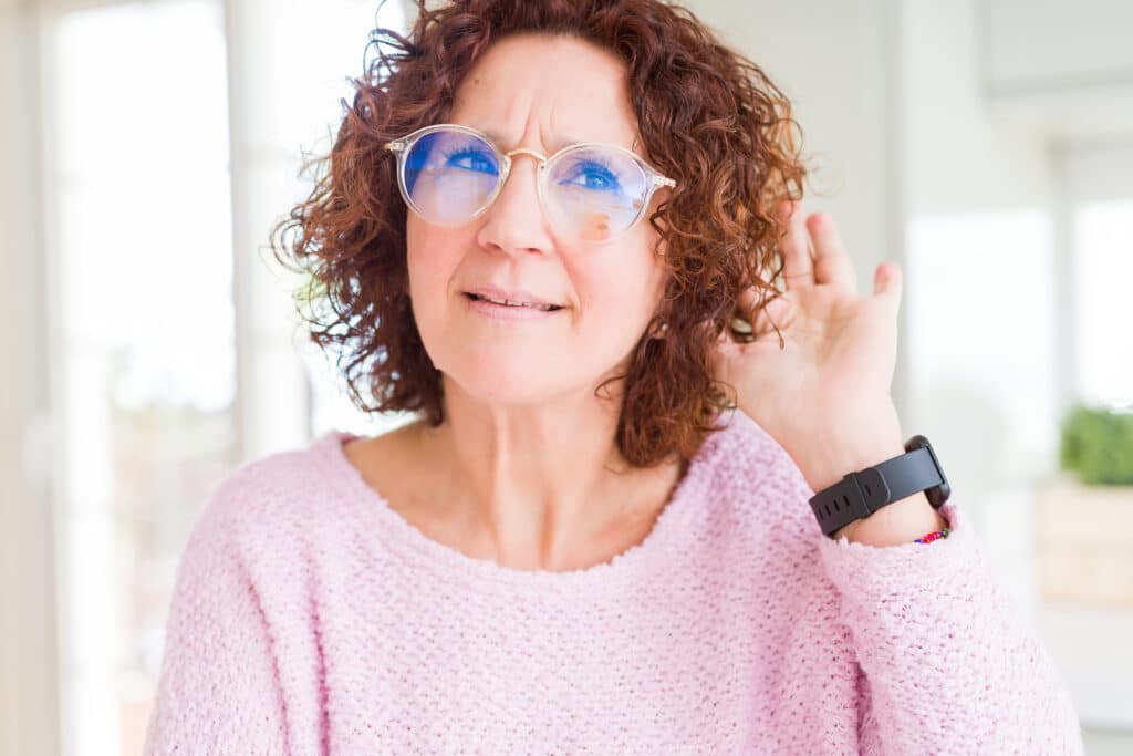 A woman with diabetes and hearing loss holding her hand up to her ear