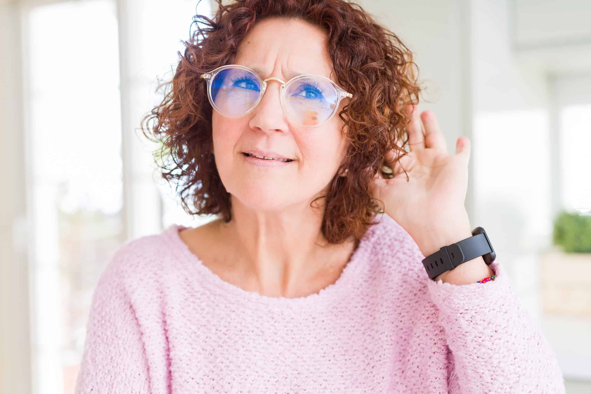 A woman with diabetes and hearing loss holding her hand up to her ear