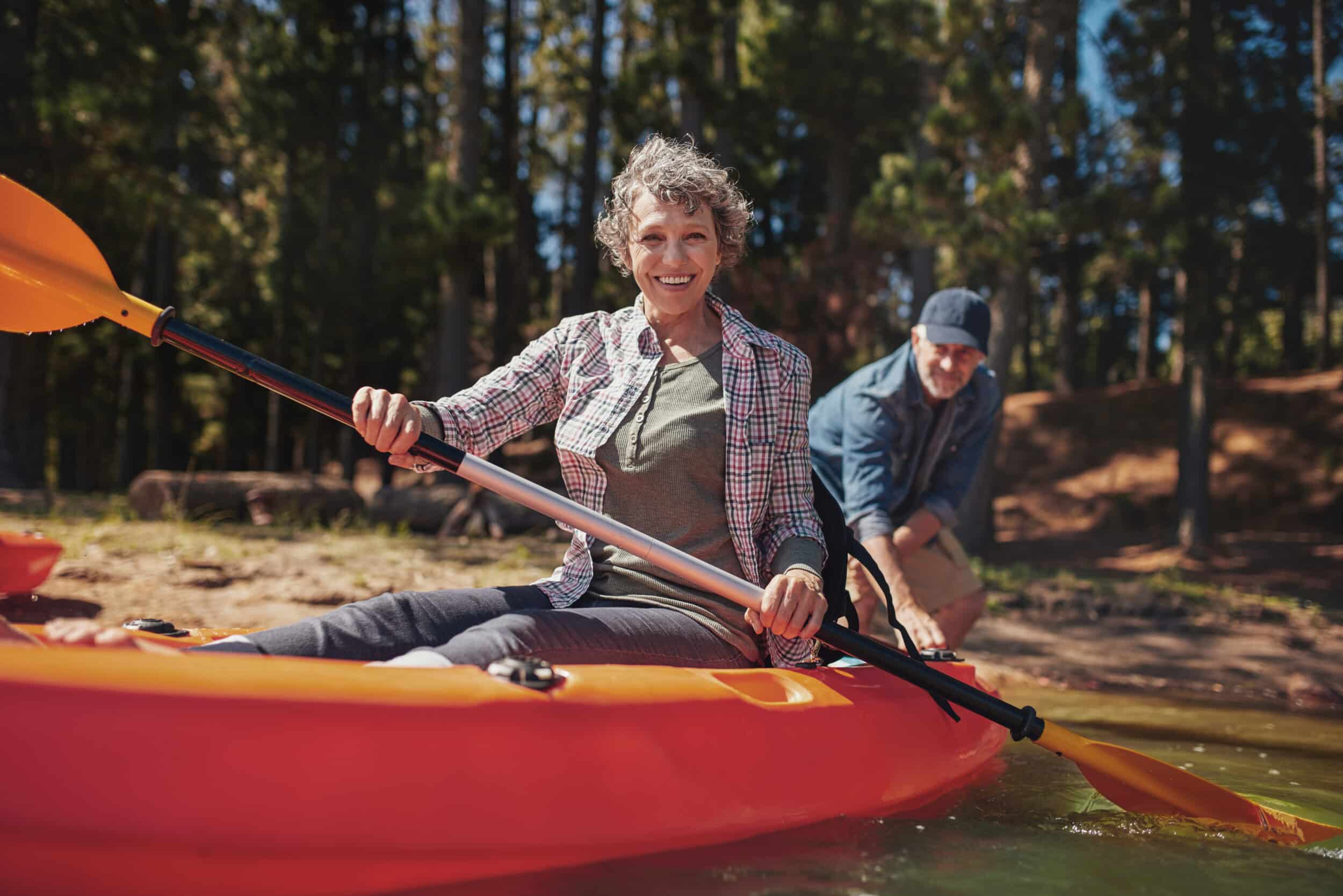 Two seniors smiling and kayaking