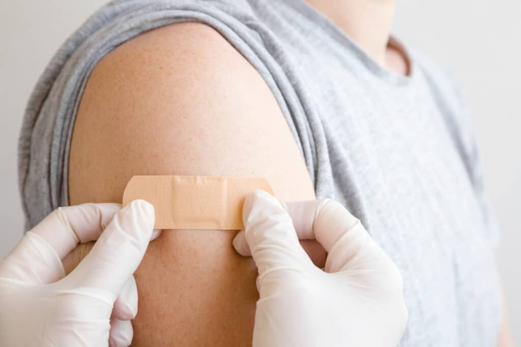 A doctor placing a bandage on a person's arm after getting a flu shot