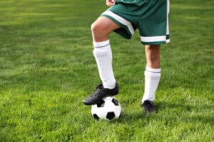 A cropped shot of a boy's legs with a soccer ball after a sports physical in Fairfax