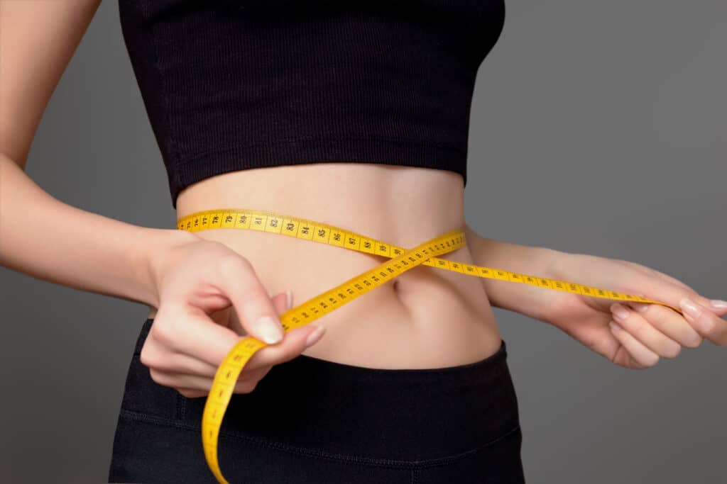 Overweight woman having a consultation with her doctor about semaglutide for weight loss. Woman wrapping tape measure around her waist